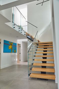 a staircase with glass railing and wooden handrails in a modern style home setting