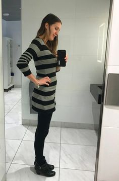 a woman standing in front of a mirror taking a selfie with her cell phone