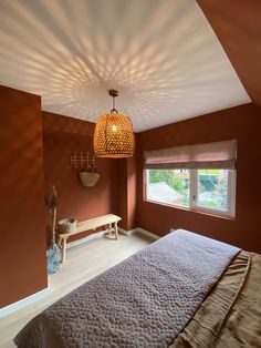 a bed room with a neatly made bed next to a window and a lamp hanging from the ceiling