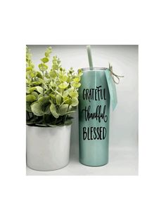 a blue tumbler next to a potted plant with the words grateful, thanks, and blessing written on it