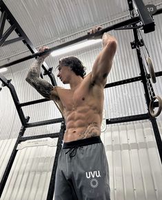 a man with no shirt on is doing pull ups