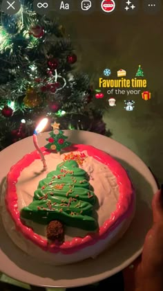 a decorated christmas cake sitting on top of a white plate next to a lit candle