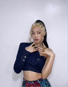 a young woman posing in front of a white wall with her hands on her hips