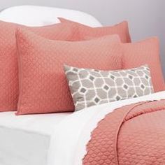 a bed with pink and gray pillows on it's headboard in a bedroom