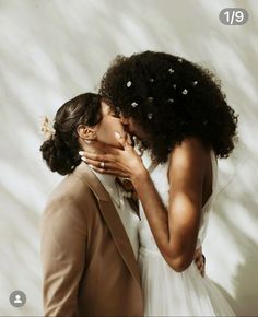 a man and woman kissing each other in front of a white wall