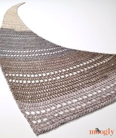 a crocheted shawl is shown on a white surface with an orange and gray stripe