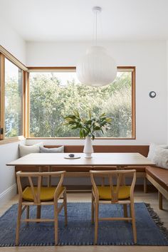 a dining room table with two chairs and a bench in front of a large window