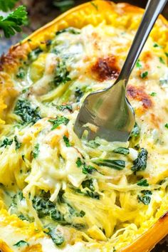 a spoon in a casserole dish with spinach and cheese on it, ready to be eaten