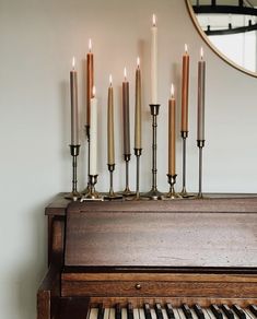 candles are lined up on top of an old piano