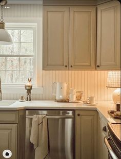 a kitchen with beige cabinets and white counter tops, an open dishwasher in the middle