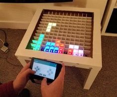 a person holding a cell phone in front of a table with colorful blocks on it