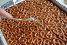 a spoon sitting on top of a metal pan filled with chocolate covered pretzels