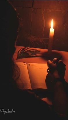 a person reading a book with a lit candle