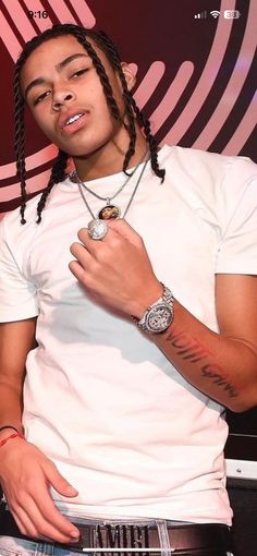 a young man with dreadlocks standing in front of a red and black background