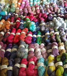 many skeins of yarn are laid out on the floor in rows and colors