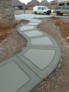 a walkway made out of concrete on the side of a road with cars parked in the background