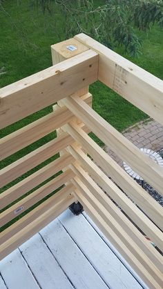 a wooden bench sitting on top of a patio next to a lush green field with lots of trees