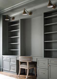 an empty room with some gray cabinets and lights on the wall, along with a chair