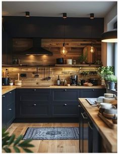 a kitchen with wooden walls and black cabinets, wood flooring, and lights hanging from the ceiling