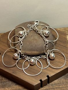 This is a beautiful, vintage, genuine, handmade Italian sterling silver circles and balls charm bracelet that was handmade in Italy. The bracelet is about 7 1/4 inches. The bracelet is just so pretty with 5 dangling sterling silver ball charms that are each 3/8" in diameter and inside a large sterling silver open circle that is 1 1/8" in diameter. Then there are 5 smaller circles in between that are each 3/4" in diameter. Very unique and well-made bracelet that has a Mid Century Modern feel to i Silver Bohemian Charm Bracelet, Handmade Silver Round Charm Bracelet, Silver Dangle Charm Bracelet, Unique Silver Dangle Charm Bracelet, Handmade Sterling Silver Charm Bracelet, Italy Vintage, Southwestern Jewelry, Jewelry Birthday, Bridal Gifts