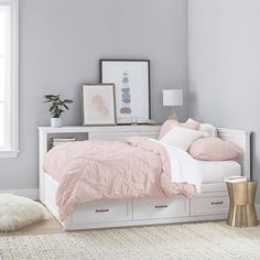 a white bed with pink sheets and pillows