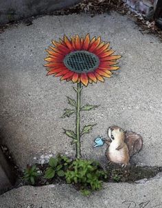 a flower painted on concrete with a squirrel looking at it's hole in the ground