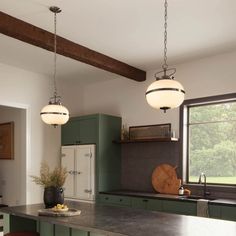 a large kitchen with green cabinets and counter tops, along with two hanging lights over the island