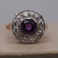 an antique amethoraite and diamond ring on top of a wooden table,