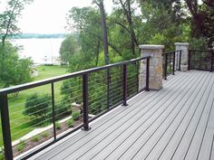 a wooden deck with black iron railings and stone pillars on the side of it