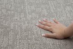 a person's hand on the ground with their left hand resting on the carpet