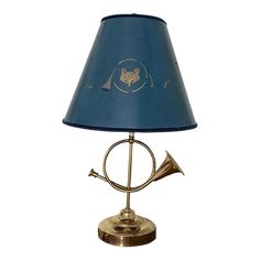 a brass lamp with a blue shade on the bottom and a gold trumpet in the middle