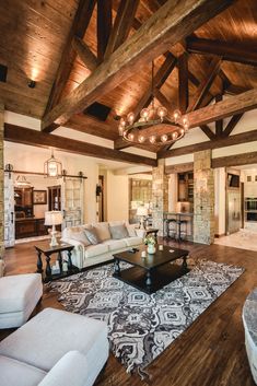 a living room filled with furniture and a chandelier hanging from the ceiling in front of a fireplace