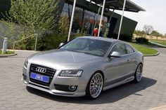 a silver car is parked in front of a building with a sign that says audi