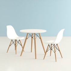 three white chairs and a table against a blue wall