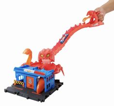 a hand is holding a plastic toy that looks like an octopus riding on a train