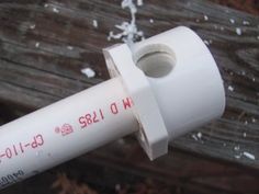 a white tube with red writing on it sitting next to a piece of wood and snow