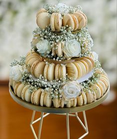 a three tiered wedding cake made out of macaroons and flowers on a stand