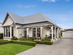 a white house with hedges in front of it