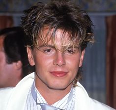 a close up of a person wearing a suit and tie with hair in the wind