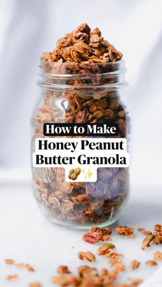 a jar filled with granola sitting on top of a white table next to a pile of nuts