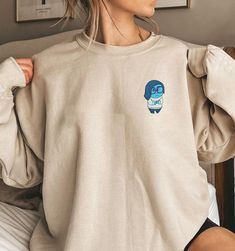 Introducing our Inside Out Character Embroidered Sweatshirt, the perfect addition to any movie lover’s wardrobe. This Cartoon Movie Shirt features vibrant and detailed embroidery of your favorite characters from the beloved film. Made from high-quality materials, it offers exceptional comfort and durability. Whether you’re planning a Family Trip or need a unique Birthday Gift, this [...] Disney Crew Neck Sweatshirt Fan Merchandise, Disney Crew Neck Sweatshirt For Fans, Disney Fan Merchandise Crew Neck Sweatshirt, Disney Embroidered Crew Neck Tops, Disney Cotton Tops With Embroidered Graphics, Disney Style Embroidered Cotton Tops, Disney Embroidered Cotton Tops, Disney Cotton Sweatshirt With Embroidered Graphics, Disney Embroidered Long Sleeve Sweatshirt