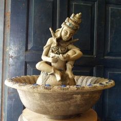 a statue of a woman holding a cat sitting on top of a stone planter