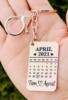 a hand holding a calendar keychain with the date on it and an apple