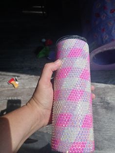 a hand holding a pink and silver cup