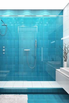 a bathroom with blue tiles and a white rug on the floor in front of it