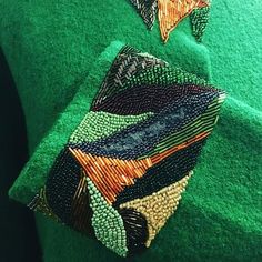 a close up of a green shirt with beads on it