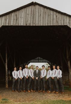 a group of men standing next to each other in front of a barn