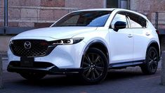 a white mazda cx - 5 parked in front of a brick building with black rims