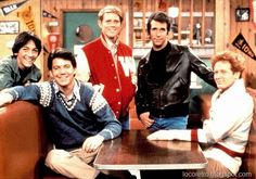 the young men are posing for a photo in front of a wooden table and chairs