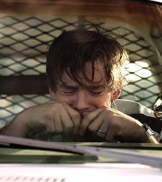 a man sitting in the back seat of a car looking at his hand on his chin